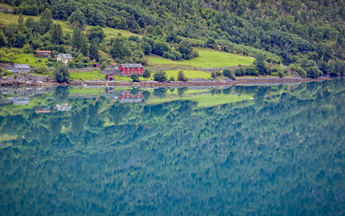 Red farmhouse reflects in the waters near Skjolden, Norway
