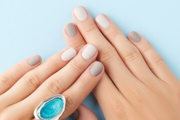 Close up womans hands with gray nail design on blue background