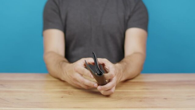 un homme ouvre un portefeuille et montre qu'il est vide