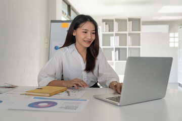 Portrait of beautiful young businesswoman asian sitting at office modern work station and typing on laptop
