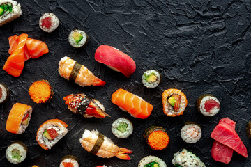 Sushi. An assortment of rolls, maki, nigiri etc, overhead flat lay shot on a black background with copy space. Japanese restaurant