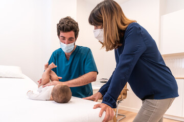 Doctor talking to a mother while checking up a baby
