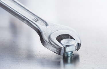 Wrench tightens bolt in steel billet. Spanner, bolt, screw and nuts.