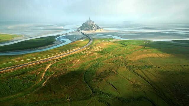 Aerial drone view of Mont-Saint-Michel in Normandy, France. Green fields, rivers and road