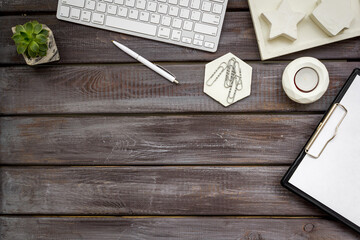 Workspace with diary, computer keyboard and succulent, top view
