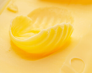 Butter curl over the piece of the butter closeup. Food background.