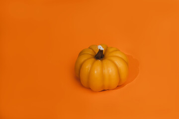 Wax yellow candle in the form of pumpkin in an orange seamless background. Autumn, Halloween background. Top view