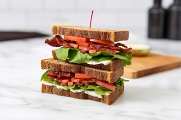 a blt sandwich with extra lettuce on a marble countertop