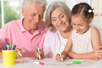 girl with grandparents drawing at the table