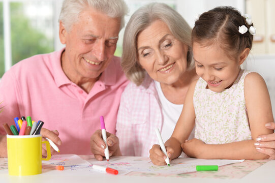girl with grandparents drawing at the table