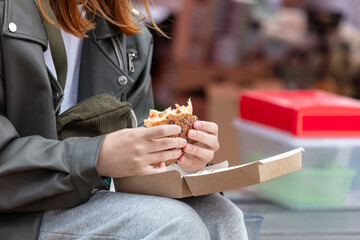 A woman eats a Burger on the street in the city