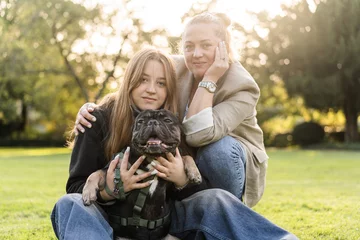 Foto op Canvas A young teenage girl with her mother hugs her French bulldog  © Rock and Wasp