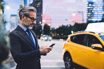 Middle aged businessman typing on smartphone against New York road