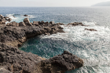 Porto do Seixal breakwater and coastal rocks. Summer landscape of Madeira