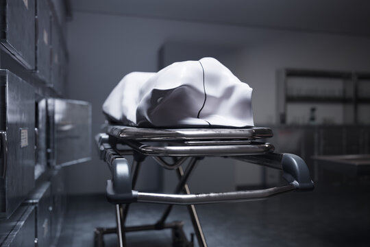 A deceased person lying on a table in a morgue, covered with a white sheet