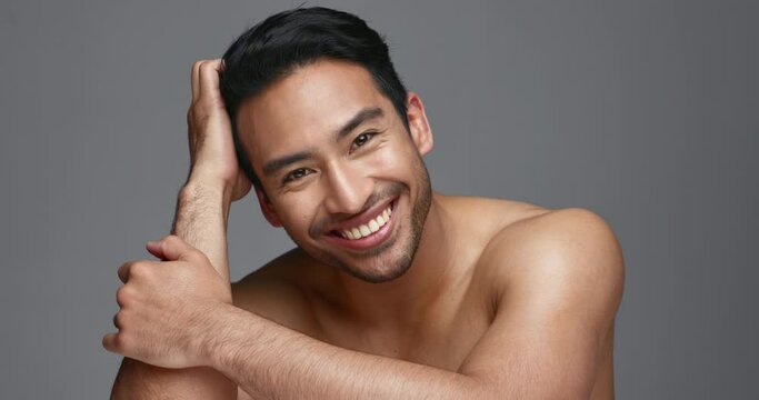 Face, cosmetics and Asian man with skincare, smile and dermatology on a grey studio background. Portrait, Japanese person and happy model with wellness, luxury treatment and beauty with aesthetic