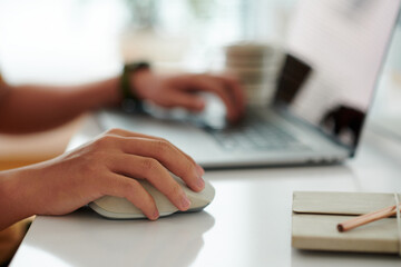 Closeup image of software developer working on computer, focus on hand with computer mouse