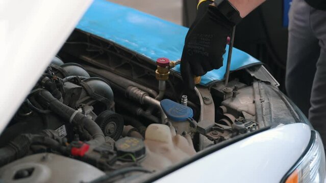 Car mechanic with manometer to fill the gas in the car air conditioning compressor. Service of checking the car air conditioner. Refrigerant recharge system.