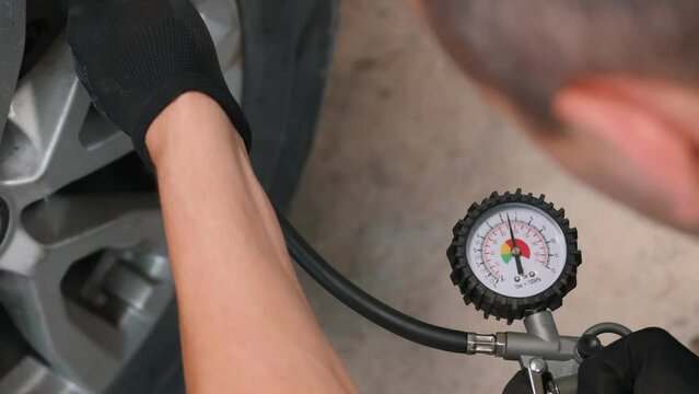 close-up, car mechanic inflating car tires in the workshop.