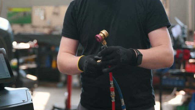 Car mechanic with manometer to fill the gas in the car air conditioning compressor. Service of checking the car air conditioner. Refrigerant recharge system.