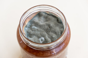 Open jar with sweet jam and mold on a white background. Mold in a jar of raspberry jam. Hazardous to health. 