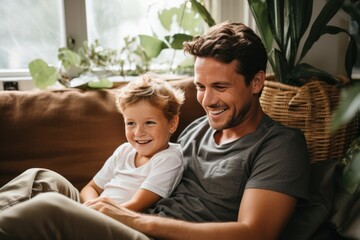 Fototapeta premium happy father using laptop while sitting by son in living room