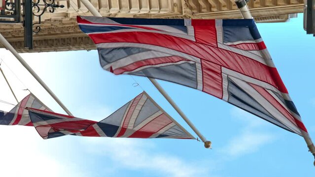 Close vertical view of flags of the United Kingdom located on facade of a building in London downtown