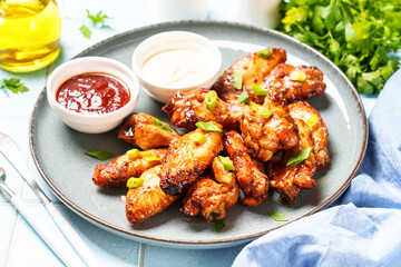 Grilled Chicken wings with sauce in craft plate at white table.