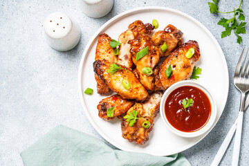 Grilled Chicken wings with sauce in craft plate at white table. Top view.