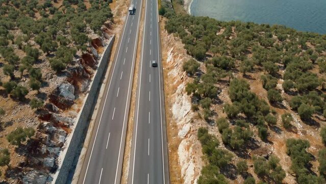 Road trips during holiday season. Cars drive along asphalt mountain road along clean river, sea, ocean and green summer forest. Aerial view from drone. Traveling by road. Bafa Lake