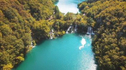 Scenic nature of waterfall with emerald pool of fresh water lake in summer green forest. Landscape of reservoir in national park.