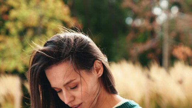 Street fashion portrait of beautiful caucasian woman outdoors. Young model in warm sweater. Fashion stylish pretty female posing in the street in city. Cheerful and happy. wind blows hair