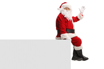 Santa Claus sitting on a wall and waving