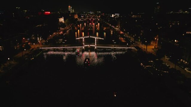 Beautiful night aerial view of Amsterdam downtown from above with many narrow canals, illuminated streets and old historic houses, drone footage