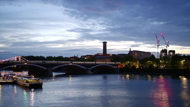 Cityscape of the London at evening, United Kingdom. Thames river, train moving on the bridge, greenery and buildings with illumination