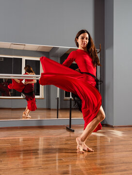 Girl in red dress are training in dance studio