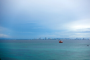 Landscape of the sea with a boat moored in the distance and the sky and a city in the distance in the background.