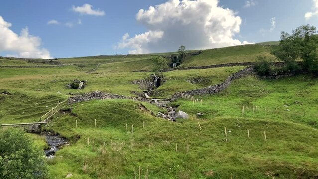 The gentle cascade of Cray Gill Waterfall in the Upper Wharfedale gentle rolling, green hills and dry stone walls of the Yorkshire Dales National Park - Nr Buckden, North Yorkshire, UK