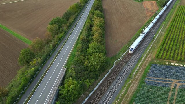 Ein ICE Zug der Bahn f&auml;hrt neben einer Stra&szlig;e durch eine Unterf&uuml;hrung, Luftaufnahme