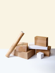 Stack of cardboard boxes, tubes and parcels on neutral background with copy space
