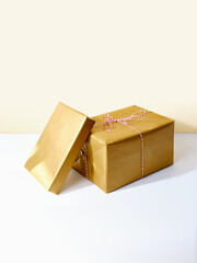 Two gift boxes, wrapped in golden paper on neutral background