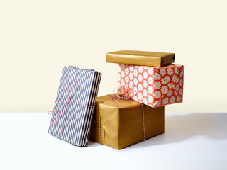 Set of holiday gifts wrapped and stacked against beige background