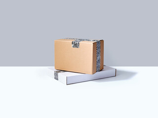 Stack of cardboard parcels packed with zebra patterned tape on neutral background