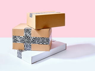 Set of cardboard boxes packed with zebra patterned tape on bright pink background