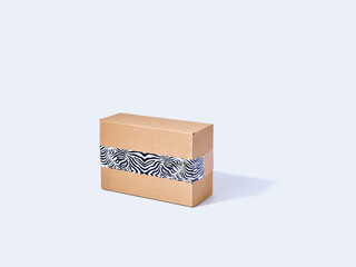 Cardboard parcel packed with zebra patterned tape on gray background with text space