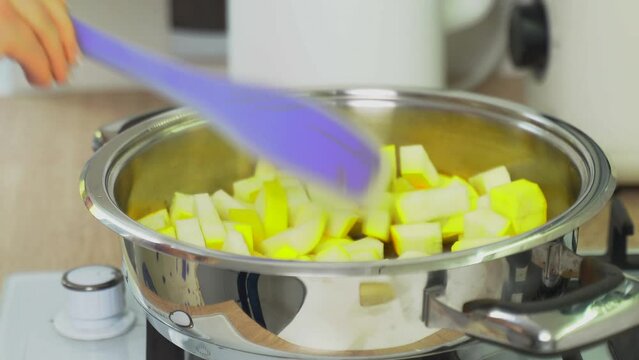 Add diced zucchini to a hot frying pan with GHI oil and cumin seeds. Cooking food.