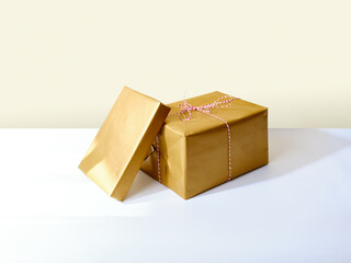Two holiday presents wrapped in golden paper on beige background