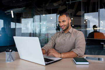 Young successful businessman working inside the office with a laptop, satisfied with the results of...