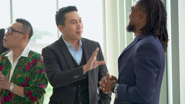 asian business man talking to african american entrepreneur with group of diverse business people  talking together in  break after meeting . communication connection