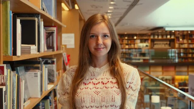 Indoor library, one person. Young female, studying. College bookcase, education. Portrait of confident student. Authentic research, bookshelf. Cheerful student in the library.